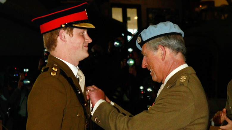 Prince Charles pinning a badge on Prince Harry military uniform