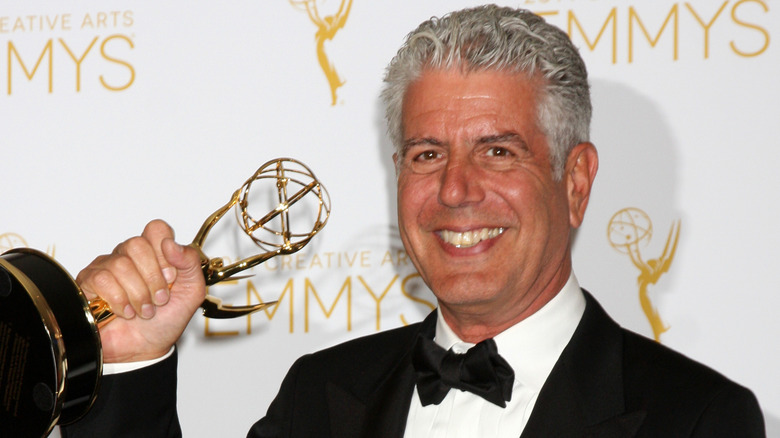 Anthony Bourdain smiling and holding an Emmy