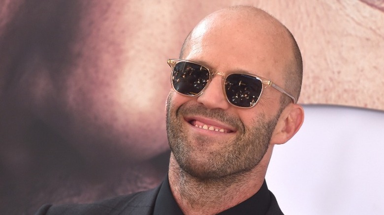 Jason Statham smiling with sunglasses on