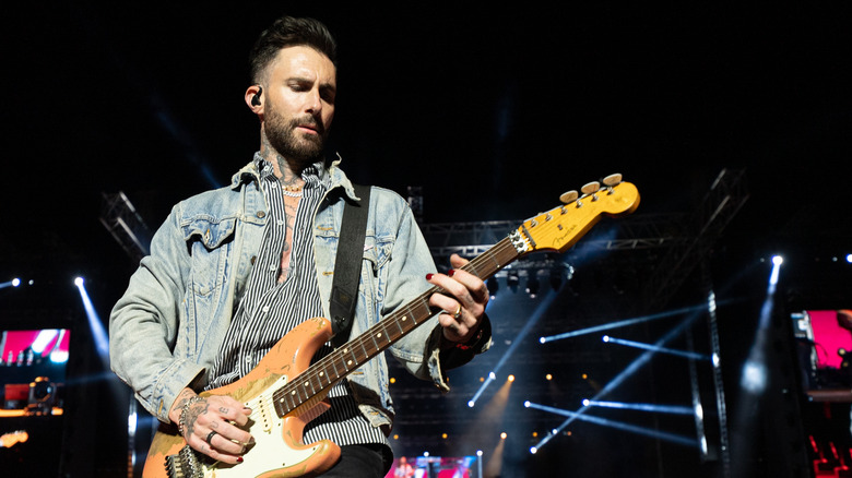 Adam Levine playing guitar on stage