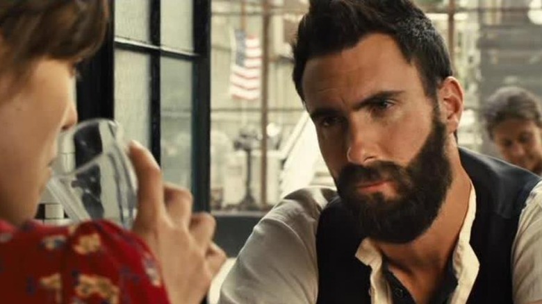 Adam Levine looking at Kiera Knightley across table