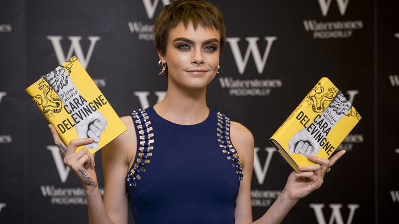 Cara Delevingne holding books smiling