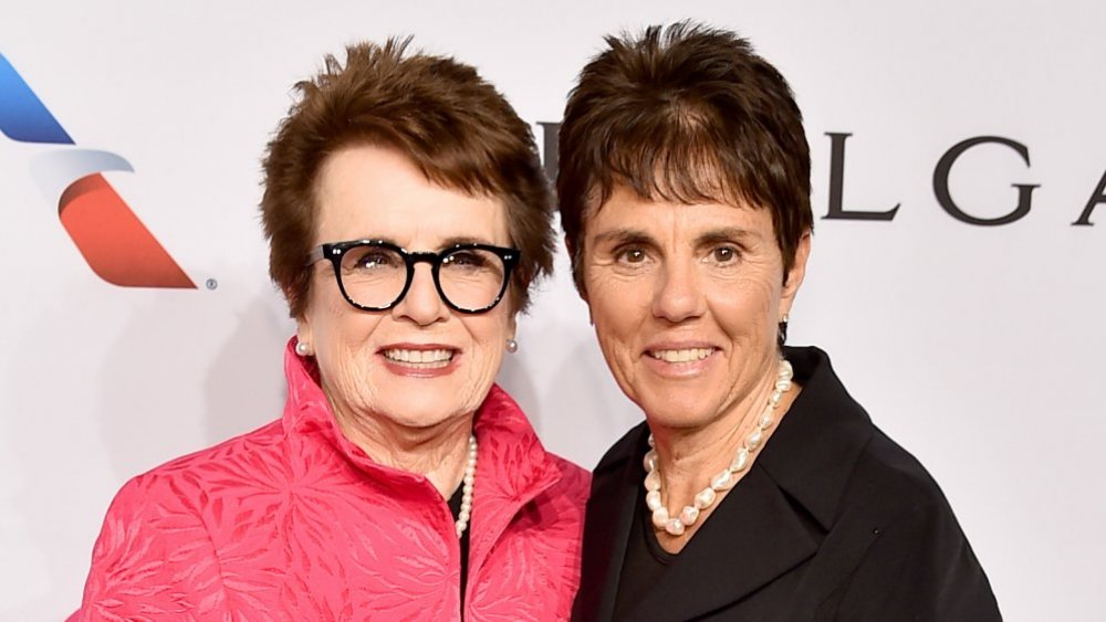 Billie Jean King in a pink jacket, partner Ilana Kloss in a black suit, smiling at an event