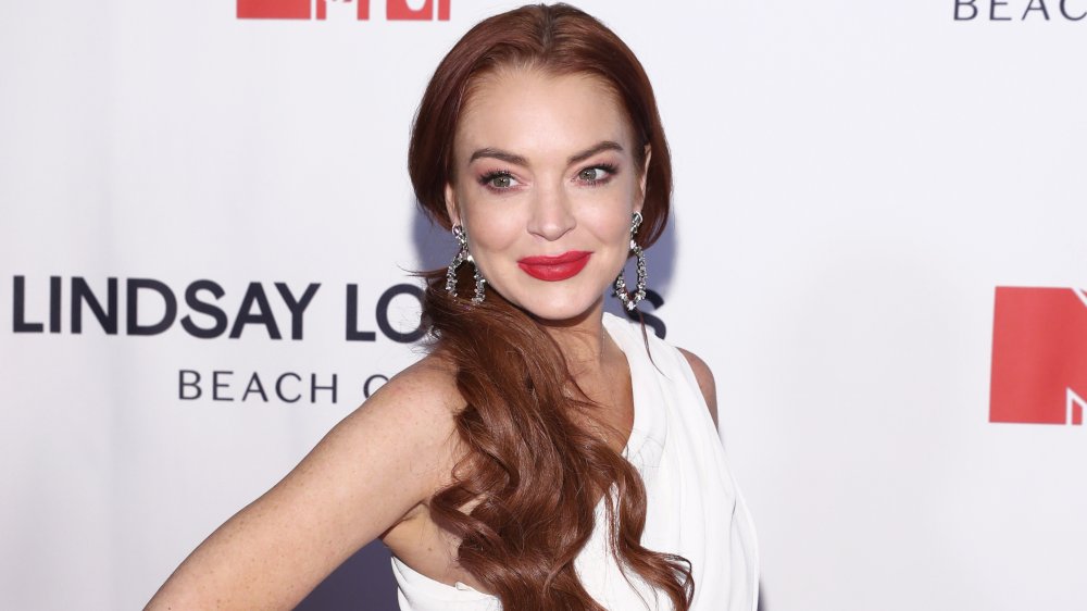 Lindsay Lohan posing with one hand on her hip in a white dress