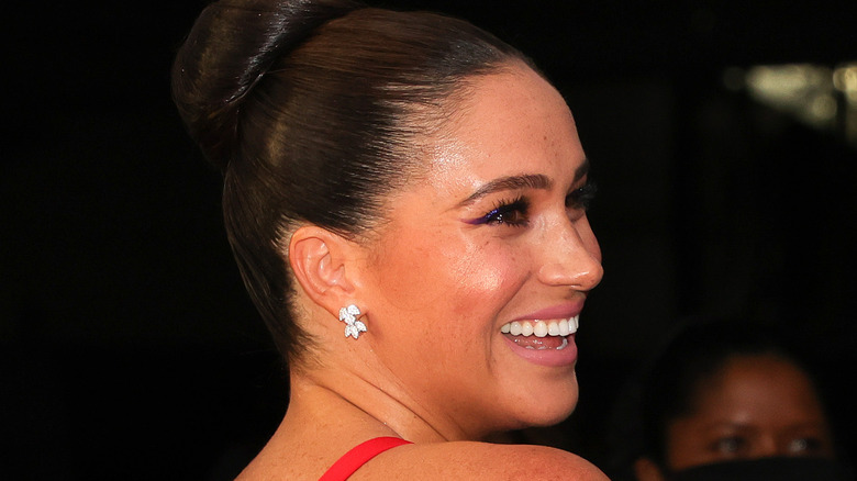 Meghan, Duchess of Sussex smiling in red gown at 2021 Salute To Freedom Gala at Intrepid Sea-Air-Space Museum