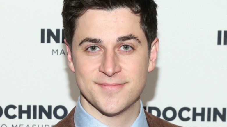 A closeup of David Henrie blue collar brown jacket