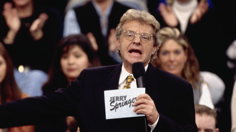 Jerry Springer holding cue cards