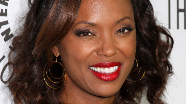 Aisha Tyler smiling with red lipstick