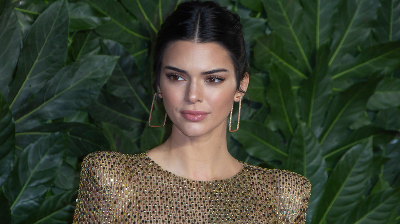 Kendall Jenner posing for a photo with gold earrings