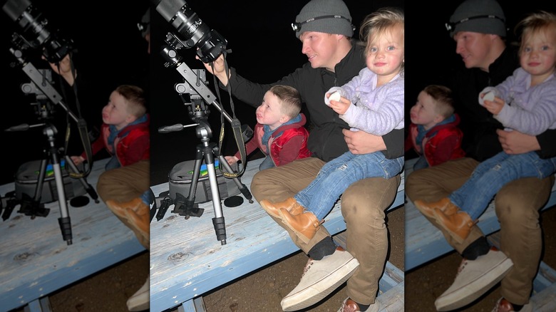 Garrison Brown and two young children looking at large camera