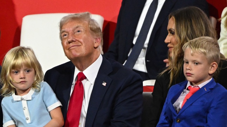 Donald Trump smiling with Lara Trump and holding Carolina and Luke Trump