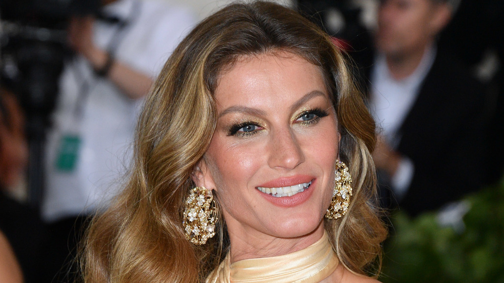 Gisele Bundchen smiles and wears large gold earrings