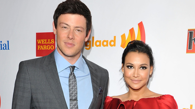 Cory Monteith tall black hair grey suit tie Naya Rivera dark hair red dress updo closed mouth smiles