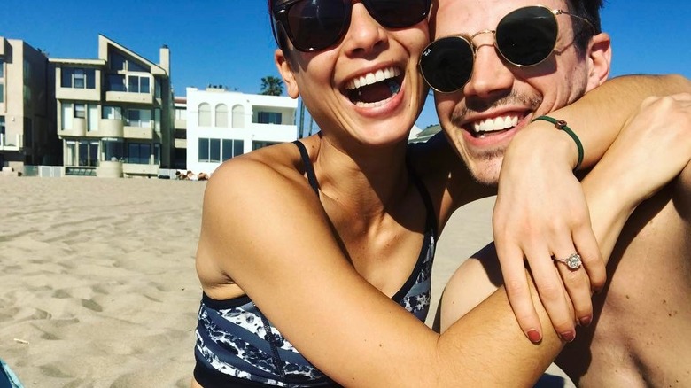 LA Thoma and Grant Gustin hugging on beach