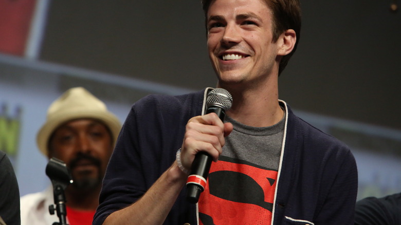 Grant Gustin smiling, holding microphone