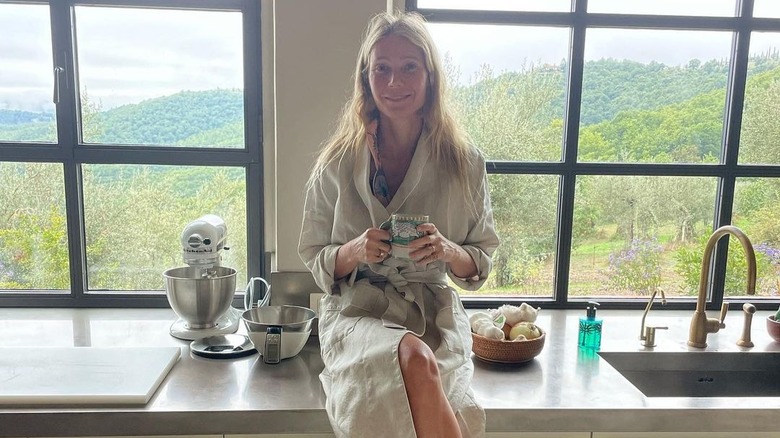 Gwyneth Paltrow seated on counter with mug