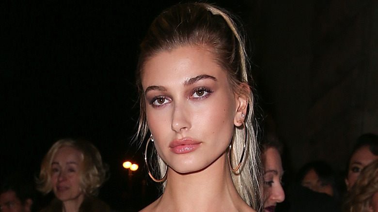 Hailey Bieber wearing gold hoops, posing