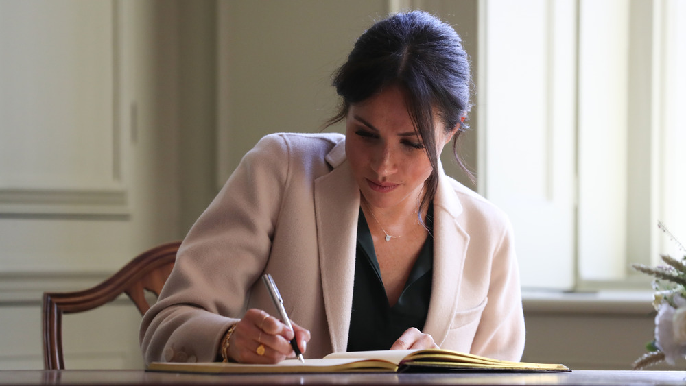 Meghan Markle writing at a desk