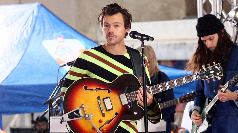 Harry Styles on stage with a guitar