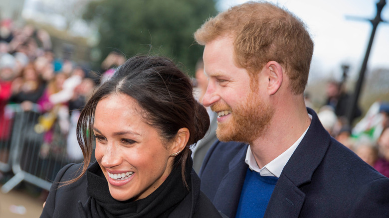 Meghan Markle and Prince Harry smiling in a crowd