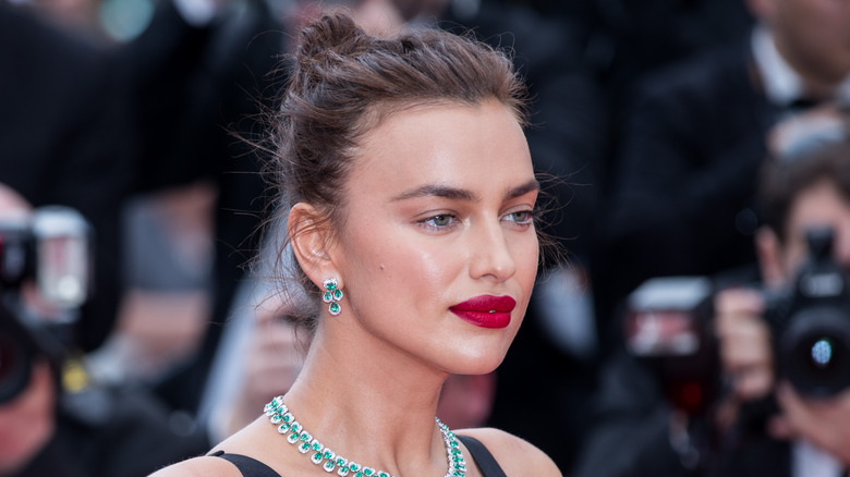 Irina Shayk poses in red lipstick and black outfit.