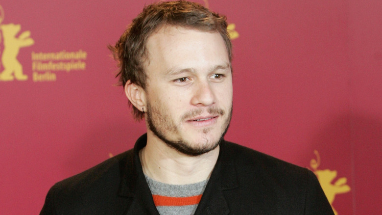 Heath Ledger wearing a black jacket over a striped shirt