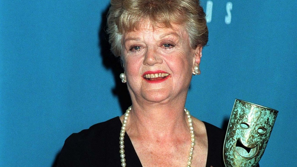 Angela Lansbury smiling while holding up an award