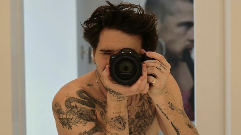 Brooklyn Beckham, taking a photo of himself looking through camera lens