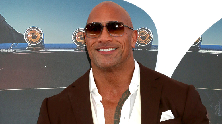 Dwayne Johnson posing in brown suit and sunglasses