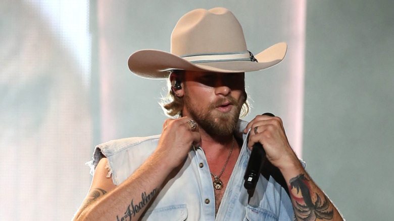 Brian Kelley, jean shirt vest, cowboy hat, facial hair, on stage, popping his collar