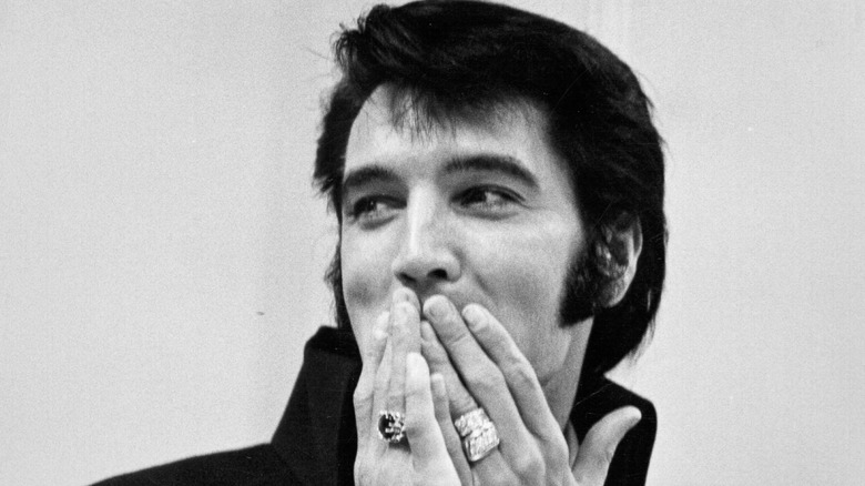 Elvis Presley covers his mouth with ringed fingers