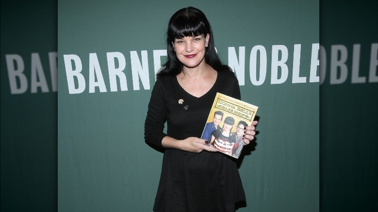 Pauley Perrette holding a cookbook