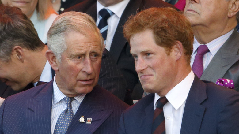 Prince Charles speaking to Prince Harry in stands