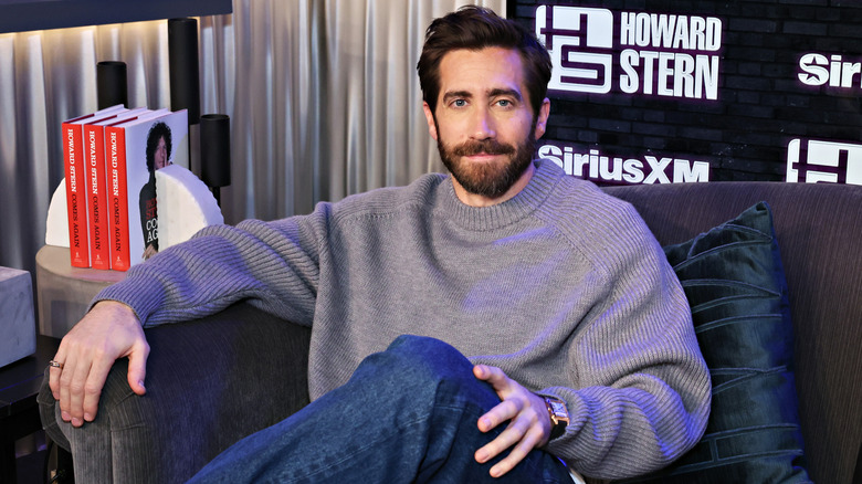 Jake Gyllenhaal sitting on a couch smiling