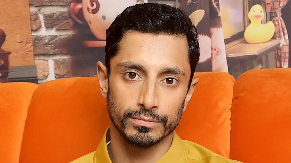 Riz Ahmed on an orange couch 