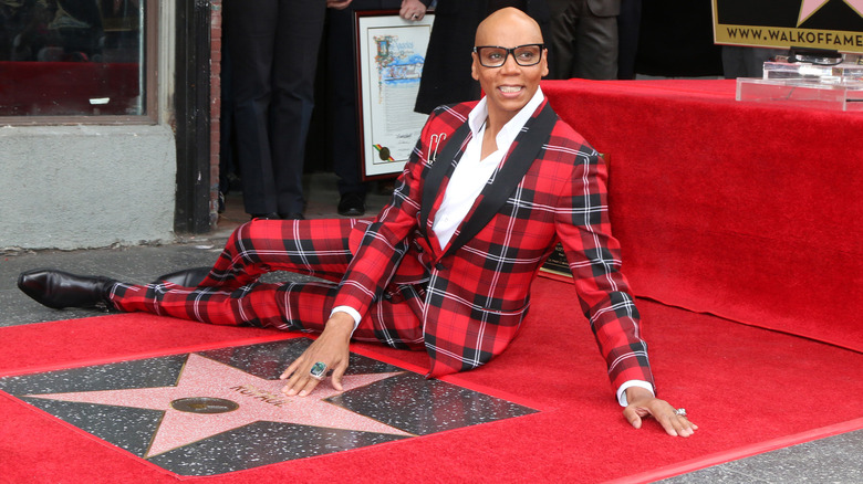 RuPaul smiling while laying on his star on the Walk of Fame