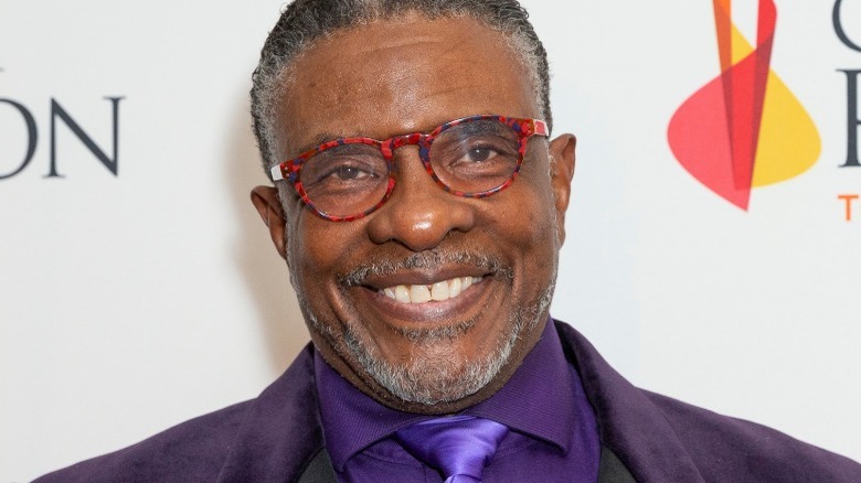 Keith David wearing a purple suit and tie, smiling