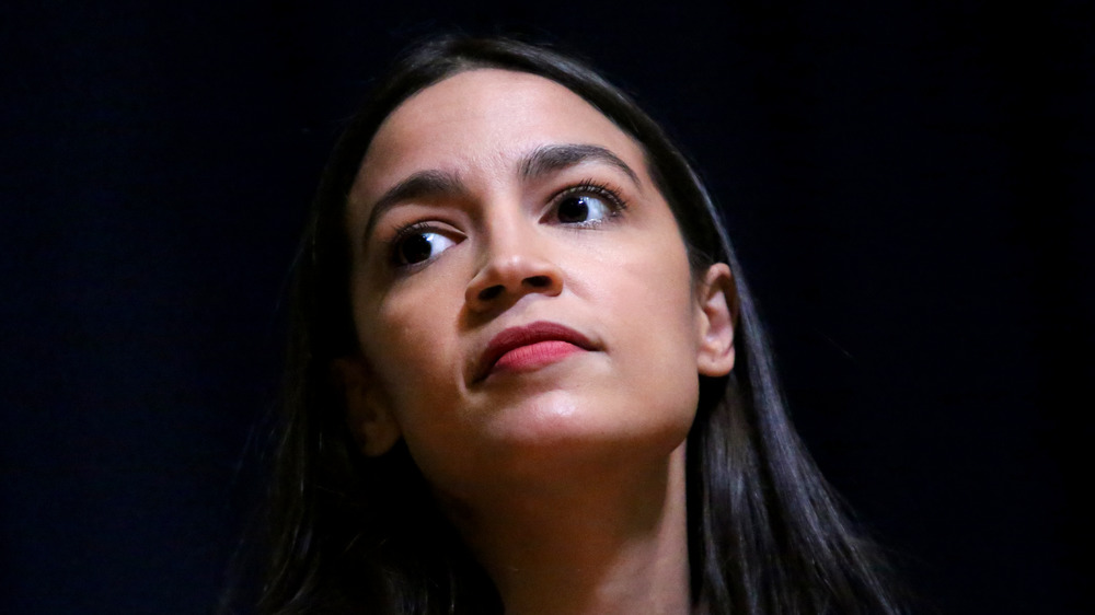 Alexandria Ocasio-Cortez posing against a black backdrop