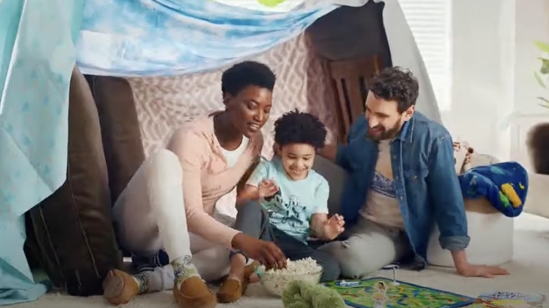 A family of three enjoying popcorn and a blanket fort in a Kohl's family fun commercial.