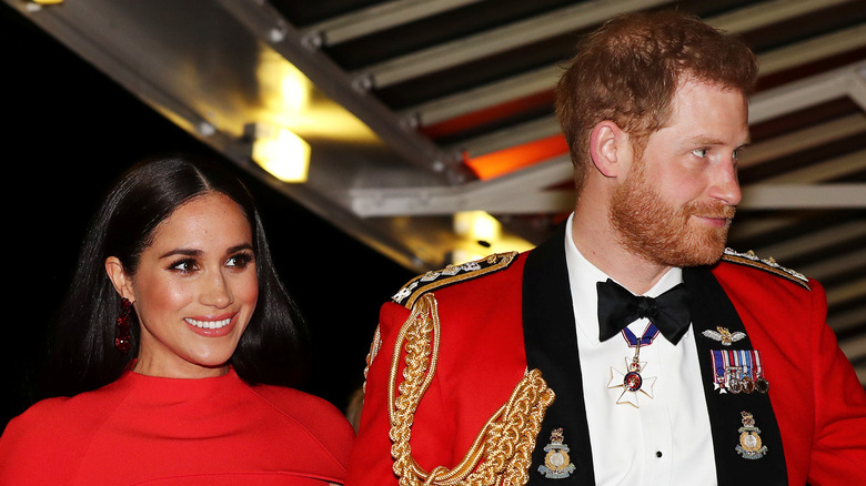 Meghan Markle and Prince Harry wearing red and smiling at event