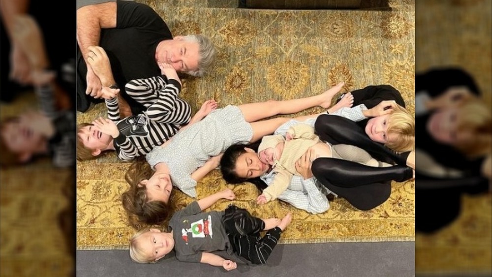 Alec Baldwin and Hilaria Baldwin with five of their six children playing on a carpeted floor