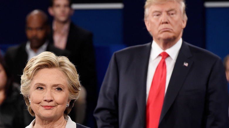 Hillary Clinton smirks in front of Donald Trump