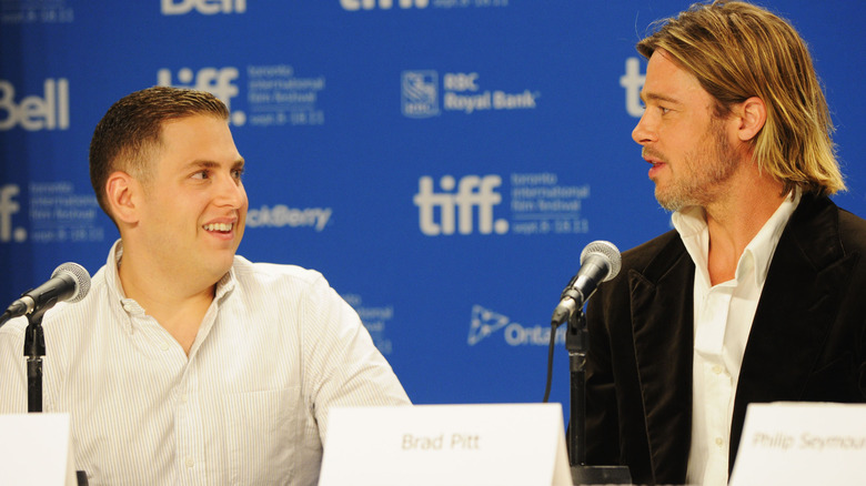 Brad Pitt and Jonah Hill smiling while on a panel