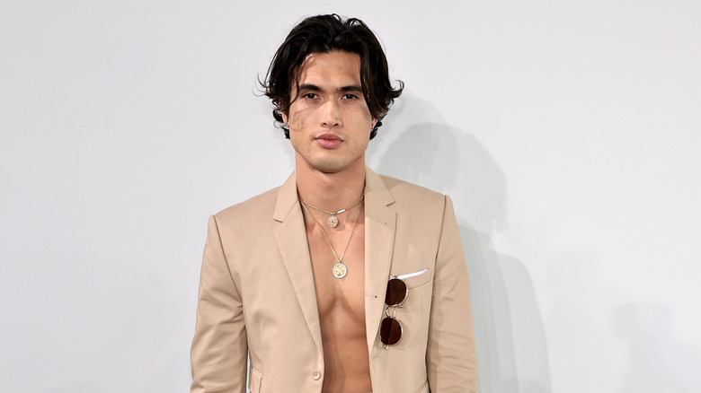 Charles Melton posing in a suit with no shirt