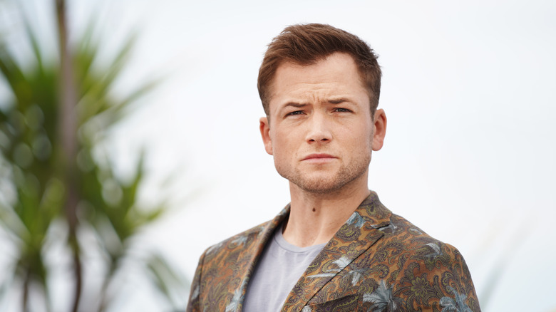 Taron Egerton posing outdoors in a suit