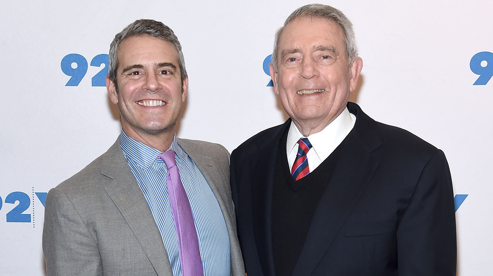 Andy Cohen, smiling, no facial hair, red carpet; Dan Rather, smiling, in a suit, red carpet