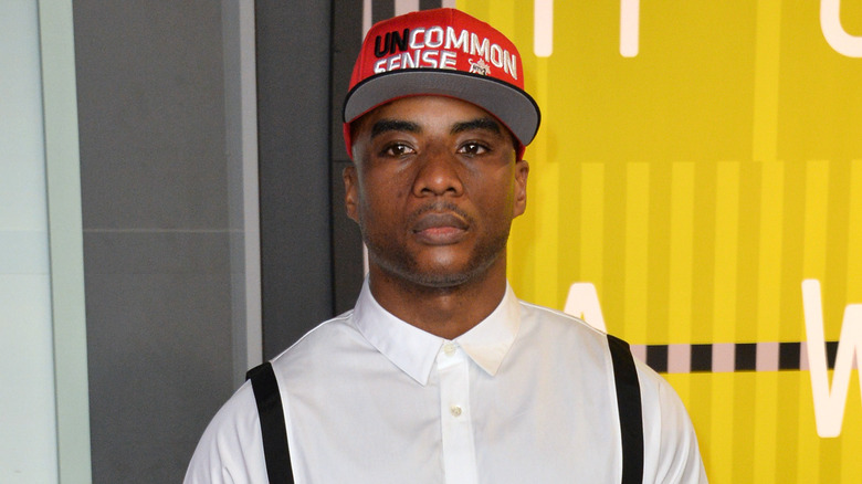 Charlamagne tha God wears a red baseball cap