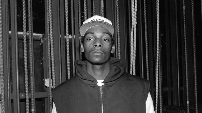 Snoop Dogg wears a baseball hat and sleeveless hoodie