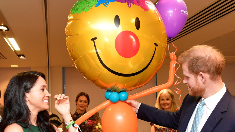 Meghan Markle and Prince Harry smiling at balloons