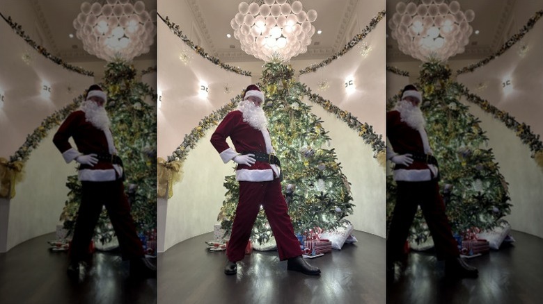 Elon Musk poses in front of a Christmas tree wearing a Santa costume